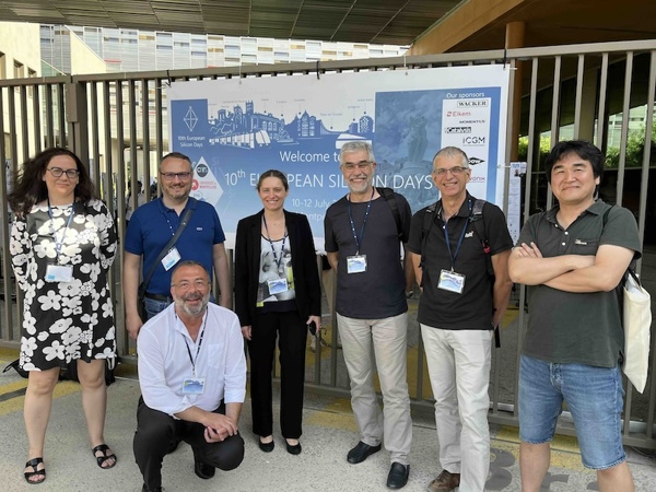 A group of people in semi-professional attire standing in front of a conference poster