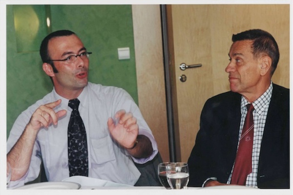 Two men in business attire seated at a table having a conversation