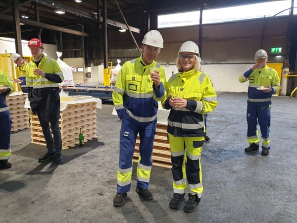 Olsen and a colleague celebrating the installation of a new robot at the plant